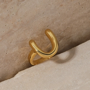 Minimalist gold U-shaped stainless steel ring displayed on a natural beige textured stone