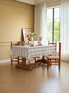 Detail of cream cotton linen tablecloth with blue stripe embroidery and tassel edges