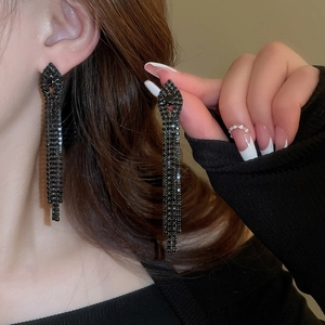 Macro shot of long black tassel earrings with crystals on a diamond-shaped base