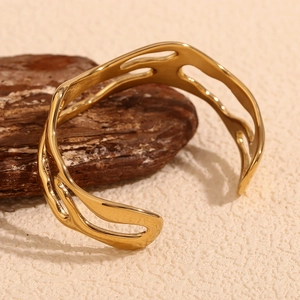 Close-up of 18K gold plated stainless steel hollow wavy bangle on elegant wood backdrop