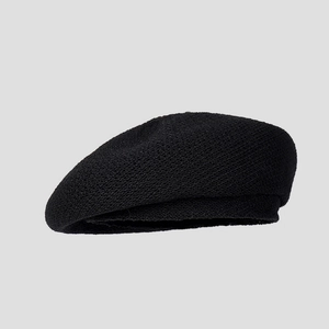 Close-up of black knitted beret showing thick yarn texture and tight weave detail