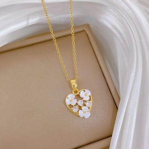 Macro shot of gold heart pendant with white shell flower and zircons on brown box