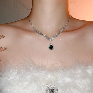 Close-up of model wearing silver necklace with green pear-shaped drop pendant and diamonds