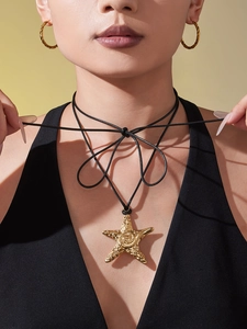 Gros plan d'un pendentif étoile de mer dorée sur cordon noir avec boucles d'oreilles