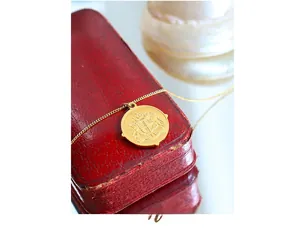 Gros plan d'un pendentif pièce vintage dorée avec relief sur écrin à bijoux élégant