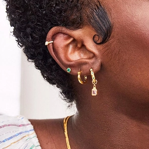 Detail of S925 silver gold-plated hoop earrings with opal and emerald green stud on ear