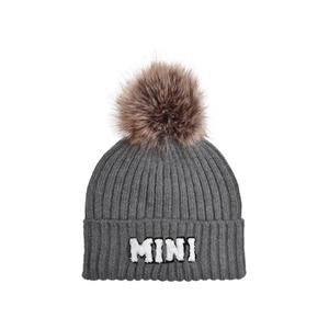 Detailed knit texture of a grey ribbed beanie with a soft brown faux fur pom-pom topper