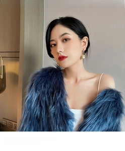 Detail of luxury pearl drop earrings with gold accents worn with blue faux fur wrap