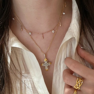 Detailed close-up of Vatican cross pendant and layered teardrop necklace on model