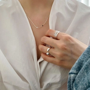 Detail of minimalist 925 silver beaded necklace and layered geometric rings on a model