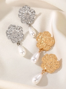 Detailed view of floral gold and silver earrings with elegant teardrop pearls on silk