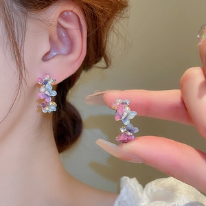 Vue détaillée de boucles d'oreilles papillon en argent avec pétales violets et perles brillantes