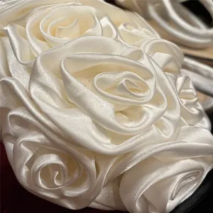 Detailed close-up of handmade 3D satin rose petals on an ivory vintage evening bag