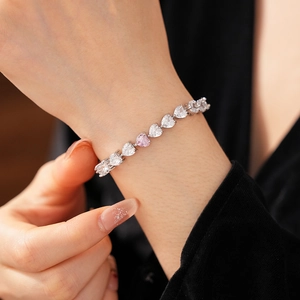 Gros plan du bracelet en zircone en forme de cœur avec pierre rose sur poignet femme