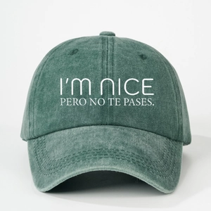 Dark green washed cotton baseball cap with white I'M NICE PERO NO TE PASES embroidery