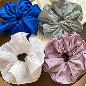 Gros plan de quatre chouchous en tissu coloré aux bords volantés et texture mate douce