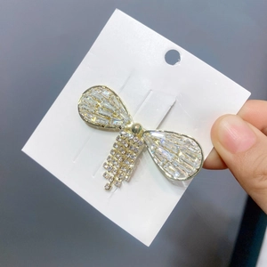 Detail of a gold alloy bow butterfly hair clip with rhinestones and tassel charms