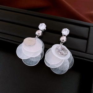 Detailed close-up of tiered white shell disc earrings with silver beads and zircon studs