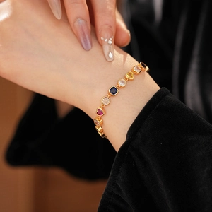 Gros plan d'un bracelet doré orné de pierres en forme de cœur et de carrés sur velours