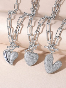 Macro shot of silver heart pendants with full zircon inlay and toggle clasp on silk