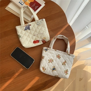Top view of two quilted cotton mini tote bags with cute bunny and bear prints on a wooden table