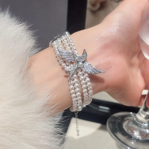 Détail d'un bracelet de perles à trois rangs avec un pendentif oiseau en zircon brillant