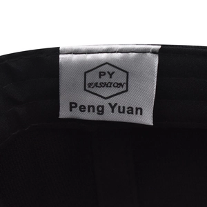 Detailed close-up of PY FASHION brand woven label stitched inside the black cotton cap