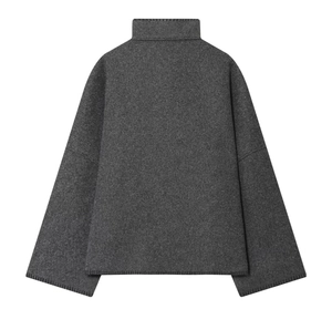 Detail view of the back of a dark grey high-neck knit sweater with textured fabric