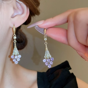 Elegante goldene Tropfenohrringe mit lila Edelsteinen und Strasssteinen an Model