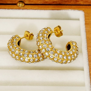 Close-up of gold-plated C-shaped hoop earrings with shimmering pavé crystal details