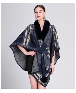 Detail of navy and beige plaid poncho featuring a faux rabbit fur collar and pompom decor