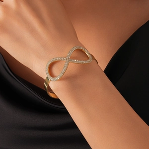 Dettaglio del bracciale a infinito dorato con zirconi sul polso di una donna