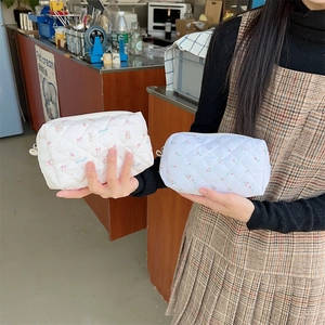 Close-up of quilted makeup bags with cute animal and cherry patterns held by a model