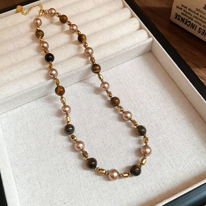 Macro detail of vintage tiger eye and pearl necklace with golden clasp in a gift box