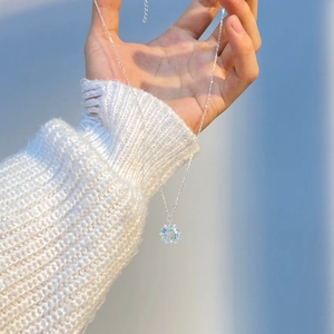 Close-up of snowflake pendant with blue topaz stone on silver chain necklace