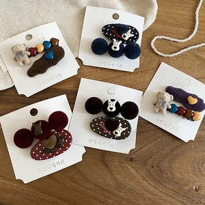 Set of flocked puppy and bear hair clips in navy blue and burgundy on wooden background