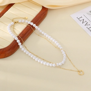 Detail of layered gold necklace with baroque pearls and heart pendant on silk tray