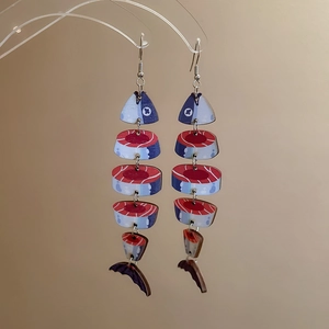 Detailed view of creative fish bone earrings with jointed wood print and colorful tassels