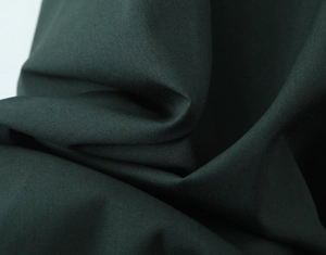 Close-up detail of dark green fabric texture with elegant folds for women dress