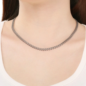Close-up of elegant silver wheat leaf chain necklace worn on neck with white collar