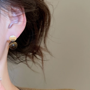 Detail of vintage 18k gold plated stud earrings featuring a tiger eye stone pendant