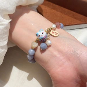 Dettaglio macro del bracciale Maneki Neko con ciondolo portafortuna al polso