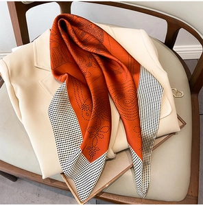 Close-up of orange polka dot silk scarf draped over a cream blazer with golden heart accessory