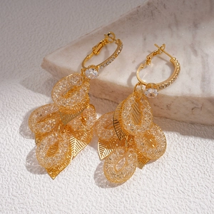 Detail of gold leaf fringe earrings with cubic zirconia accents on a marble background