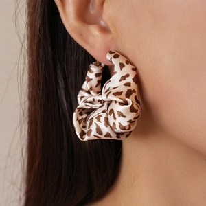 Detail shot of a leopard print fabric C-shaped earring worn on model for fashion display
