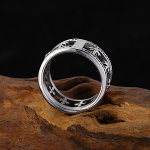 Gros plan d'une bague en acier argenté avec motifs croix sur socle en bois rustique