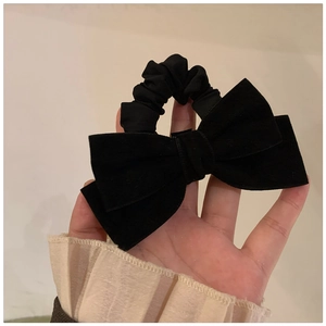 Handheld vintage black velvet bow hair scrunchie with a French minimalist aesthetic
