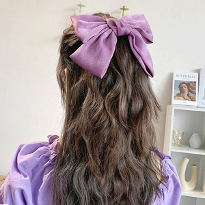 Elegant purple satin oversized bow hair tie accessory worn by model for feminine styling