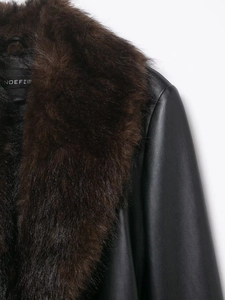 Detail of black leather coat with a large coffee-colored faux fur collar and premium texture