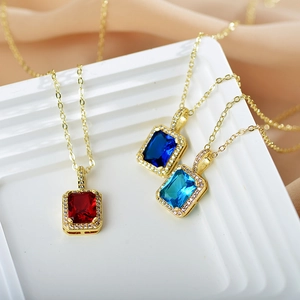 Detailed macro of gold-plated pendant necklaces featuring colorful emerald-cut gemstones